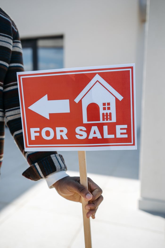 Mastering the First Impression: Your intriguing post title goes here Close-up of a hand holding a 'For Sale' real estate sign with a house icon outdoors.